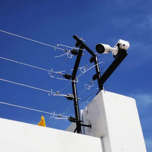 Cerco eléctrico con aisladores y una cámara sobre un muro