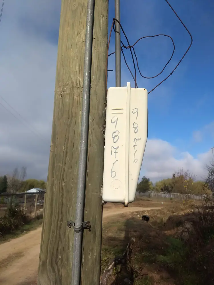 Caja de medidor instalada en un poste de madera en un camino rural