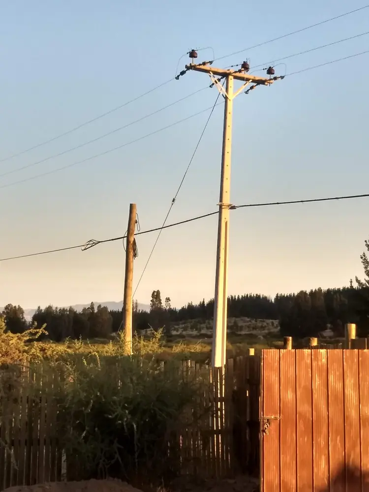 Postes con acometida en una parcela al atardecer