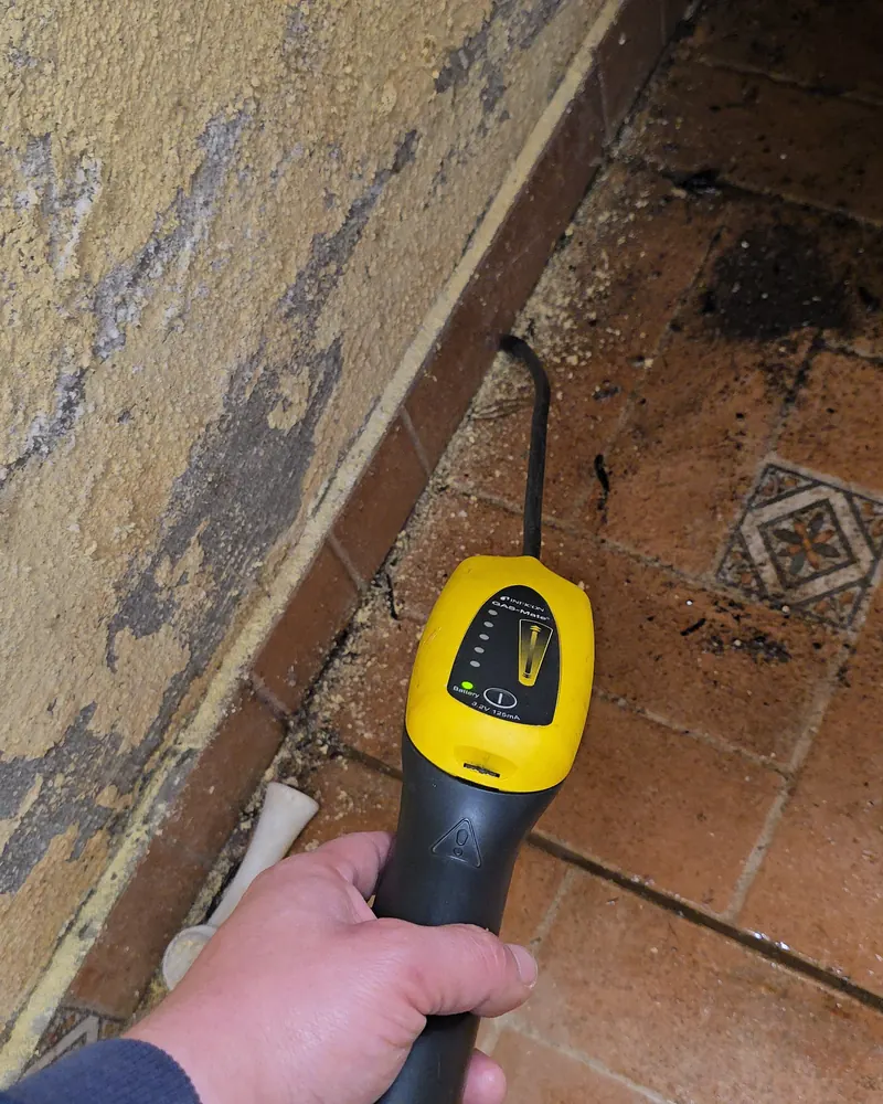 Detector de gas trazador junto a un muro con la pintura soplada por la humedad