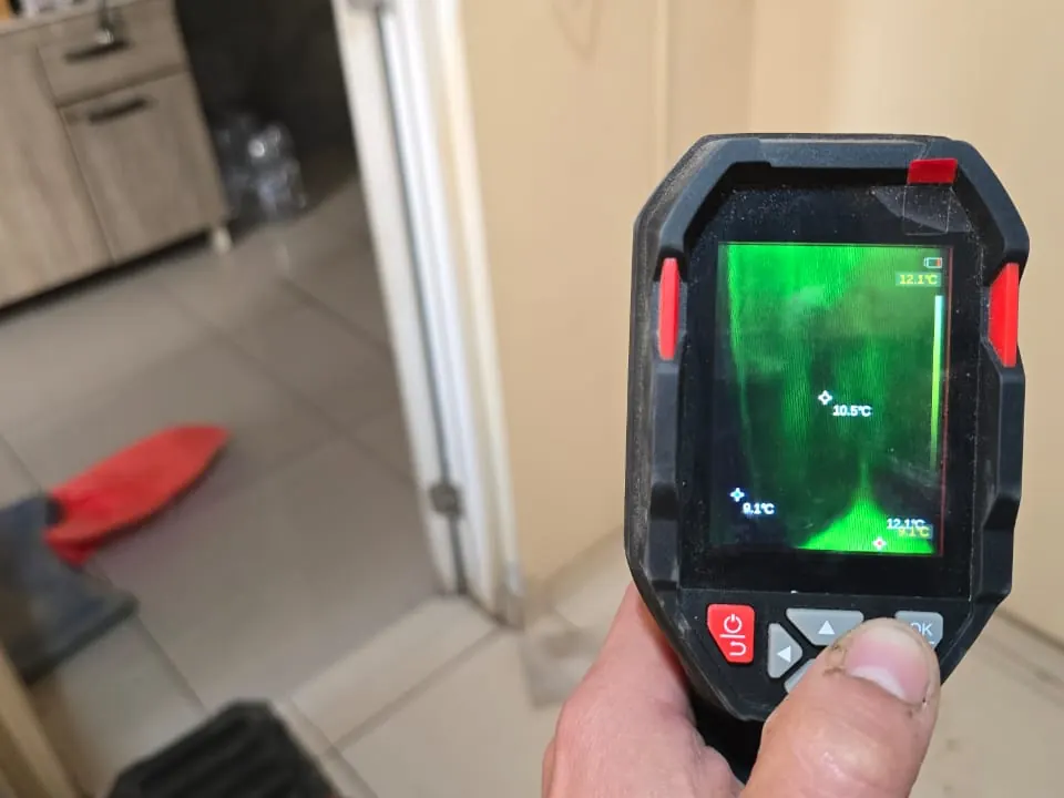 Cámara termográfica en mano mostrando en pantalla la diferencia de temperatura en el piso de una logia