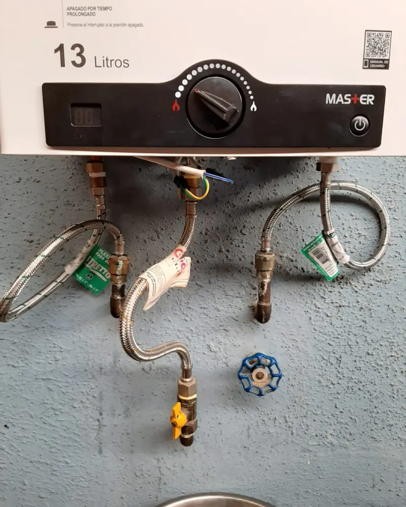 Parte inferior de un calefont de 13 litros con flexibles y llave de paso