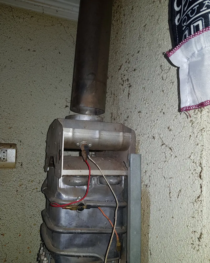 Calefont abierto en un muro exterior con el ducto conectado arriba