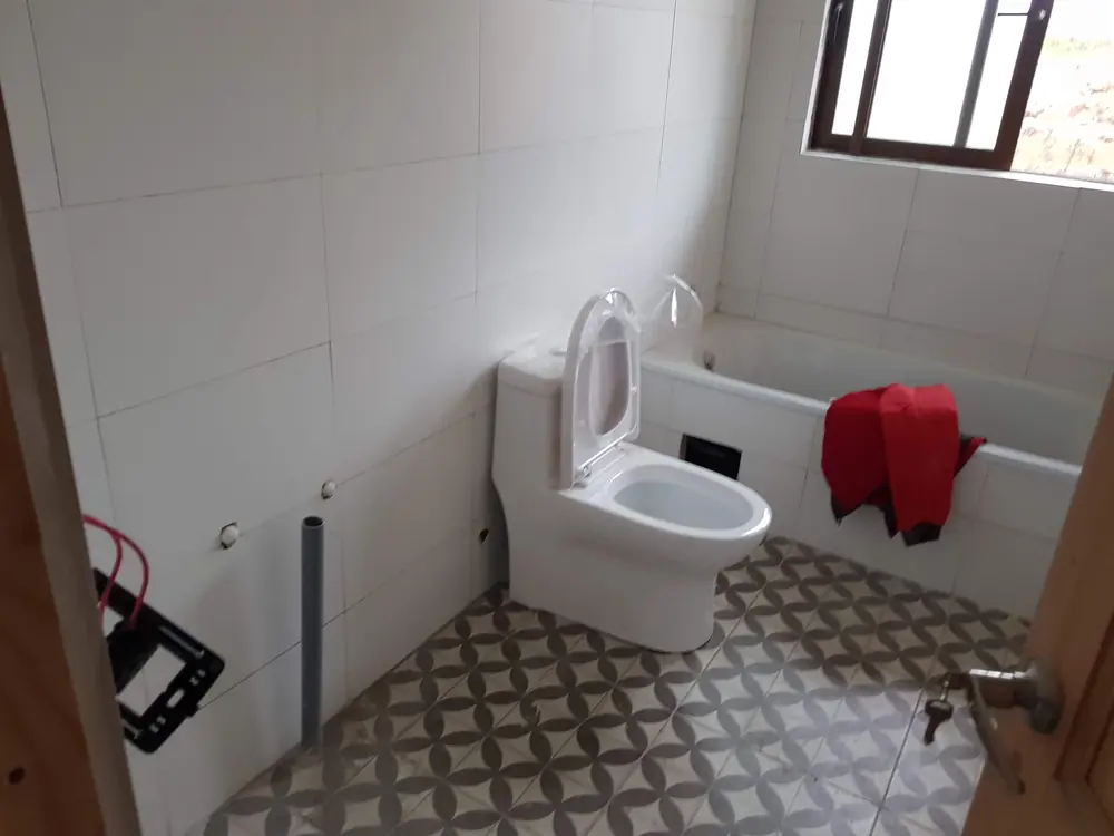 WC nuevo junto a una tina en un baño con piso de baldosa