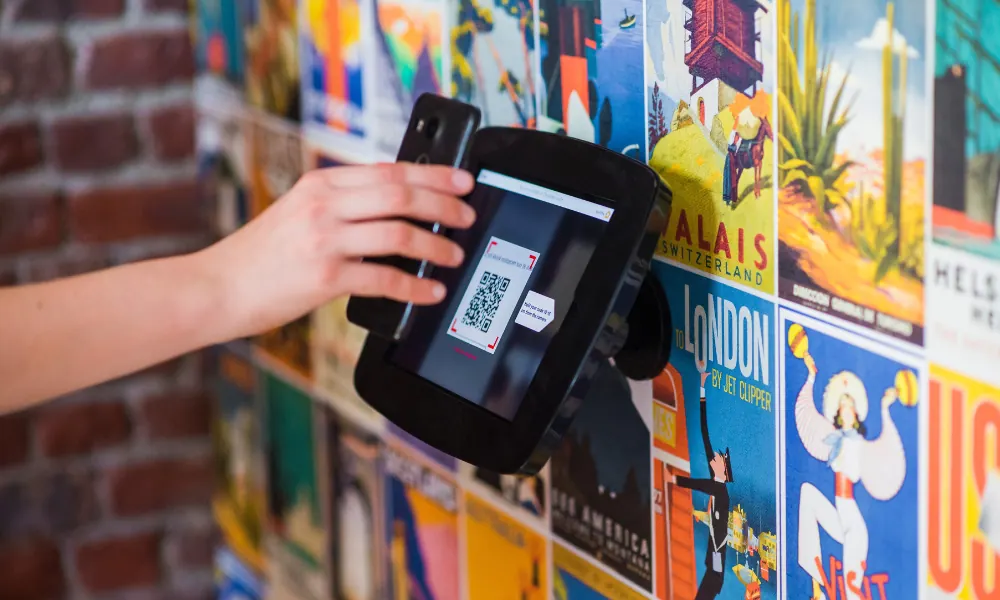 Persona mostrando un código QR en su celular a un lector de acceso