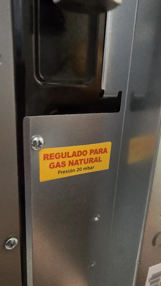 Etiqueta amarilla que dice regulado para gas natural, presión 20 mbar, en un artefacto