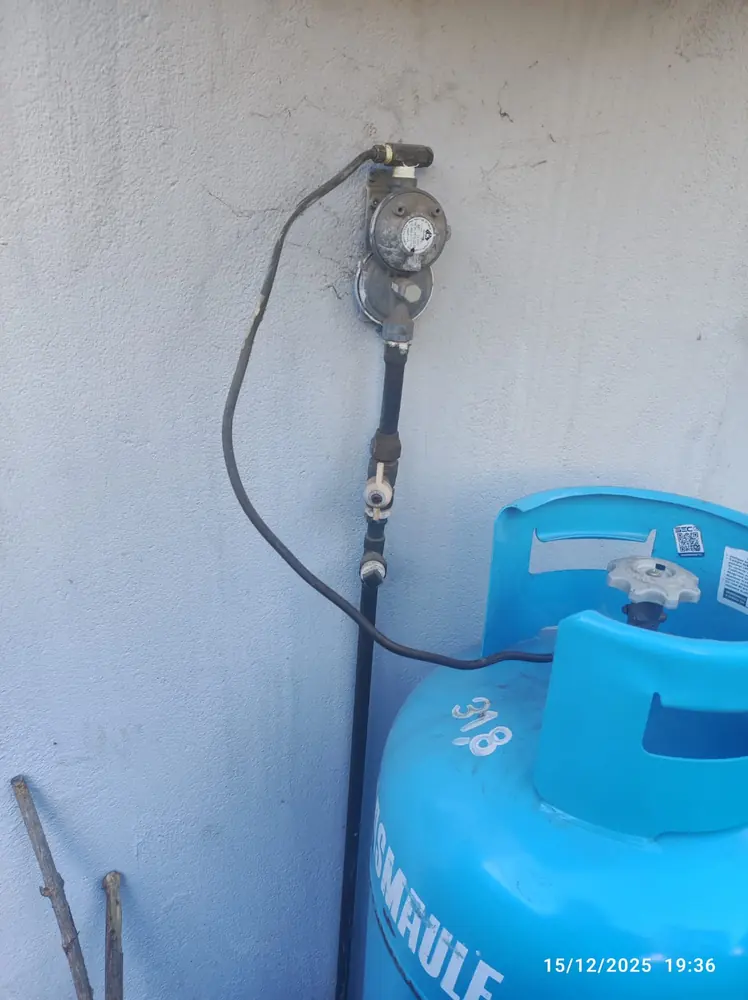 Regulador de gas en un muro blanco sobre un cilindro celeste