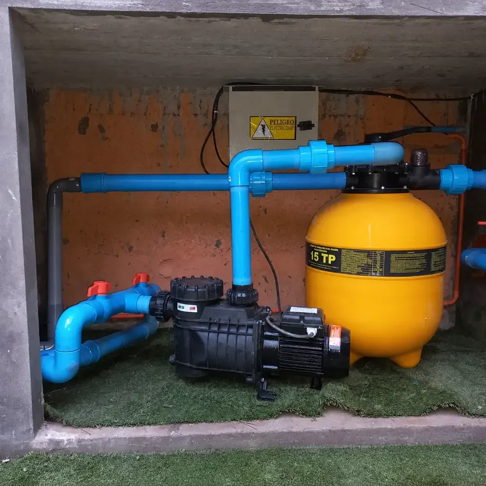 Sala de máquinas de piscina con filtro de arena amarillo, bomba y cañerías de PVC